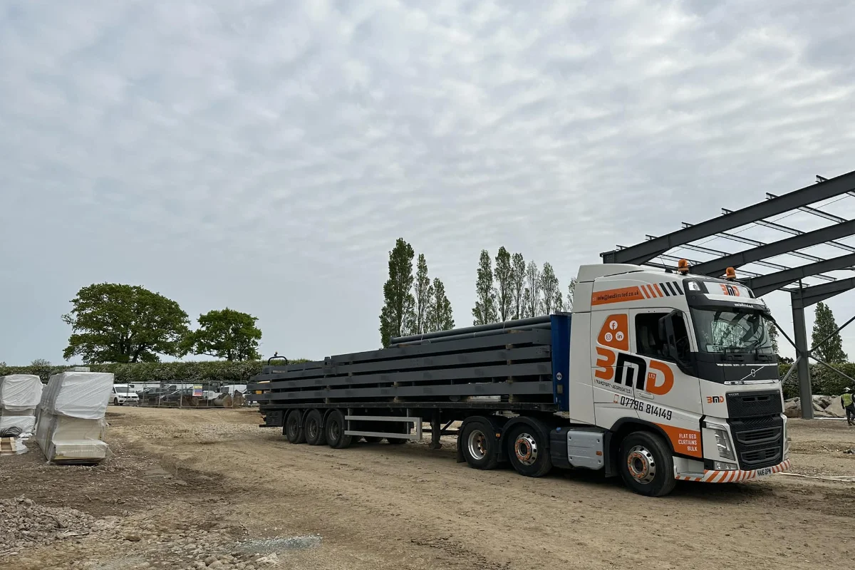 BMD flatbed lorry transporting steel beams on a construction site